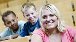 Eine Studentin und zwei Kinder sitzen im Hörsaal (Bild: Boris Loehrer/FH Köln)