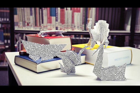 Origamitiere sind in einer Bibliothek auf Büchern angeordnet
