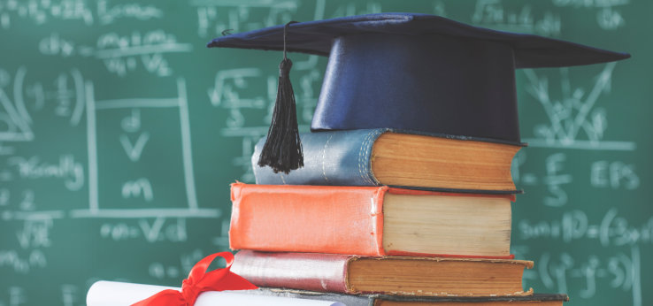  Stack books graduate hat and diploma in front of green chalkboard (Image: 196875700_sebra_AdobeStock_)